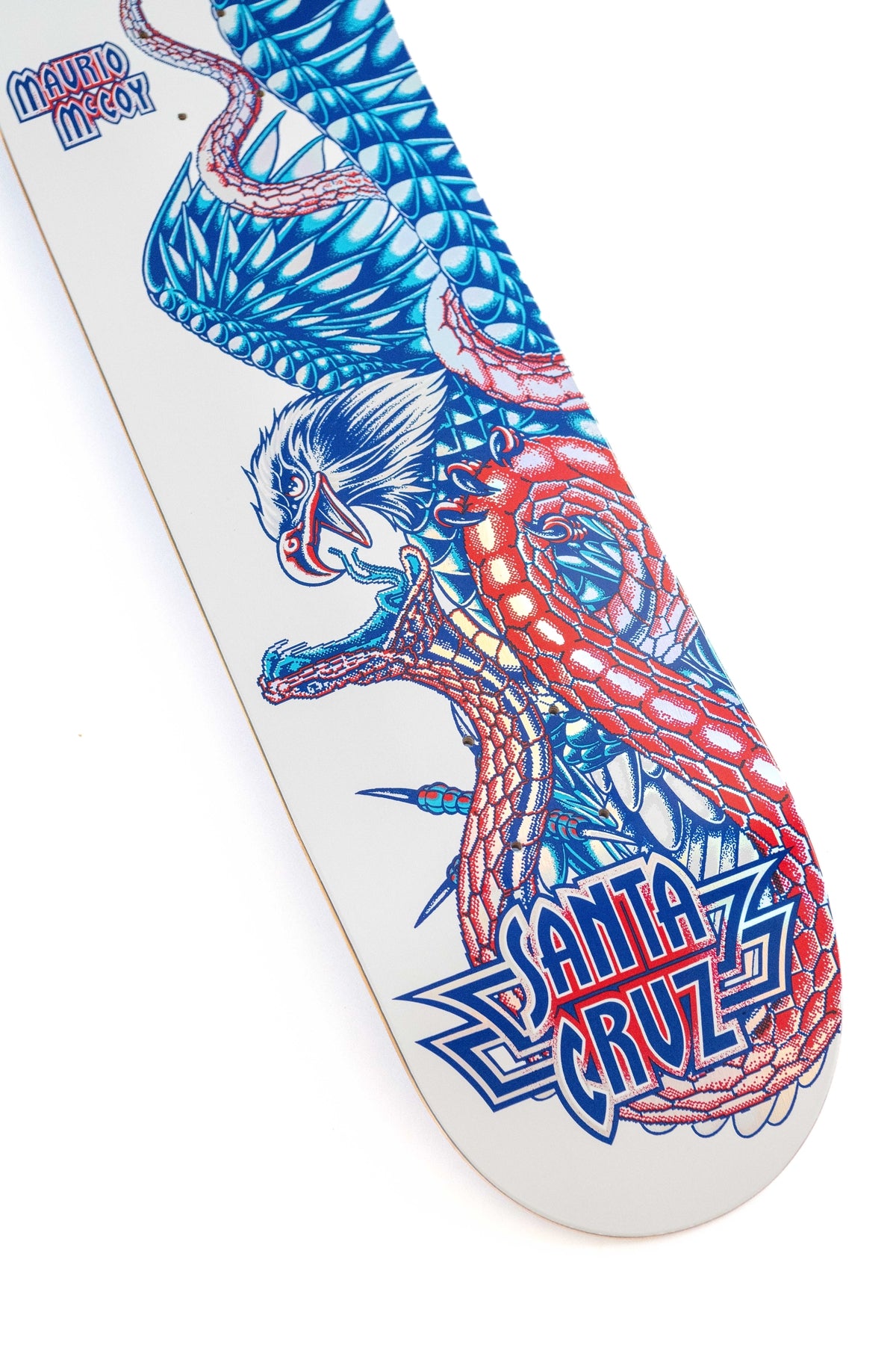 A close-up of a Santa Cruz skateboard deck featuring a detailed graphic of a blue dragon with red accents on a white background, with the 'Santa Cruz' logo visible.
