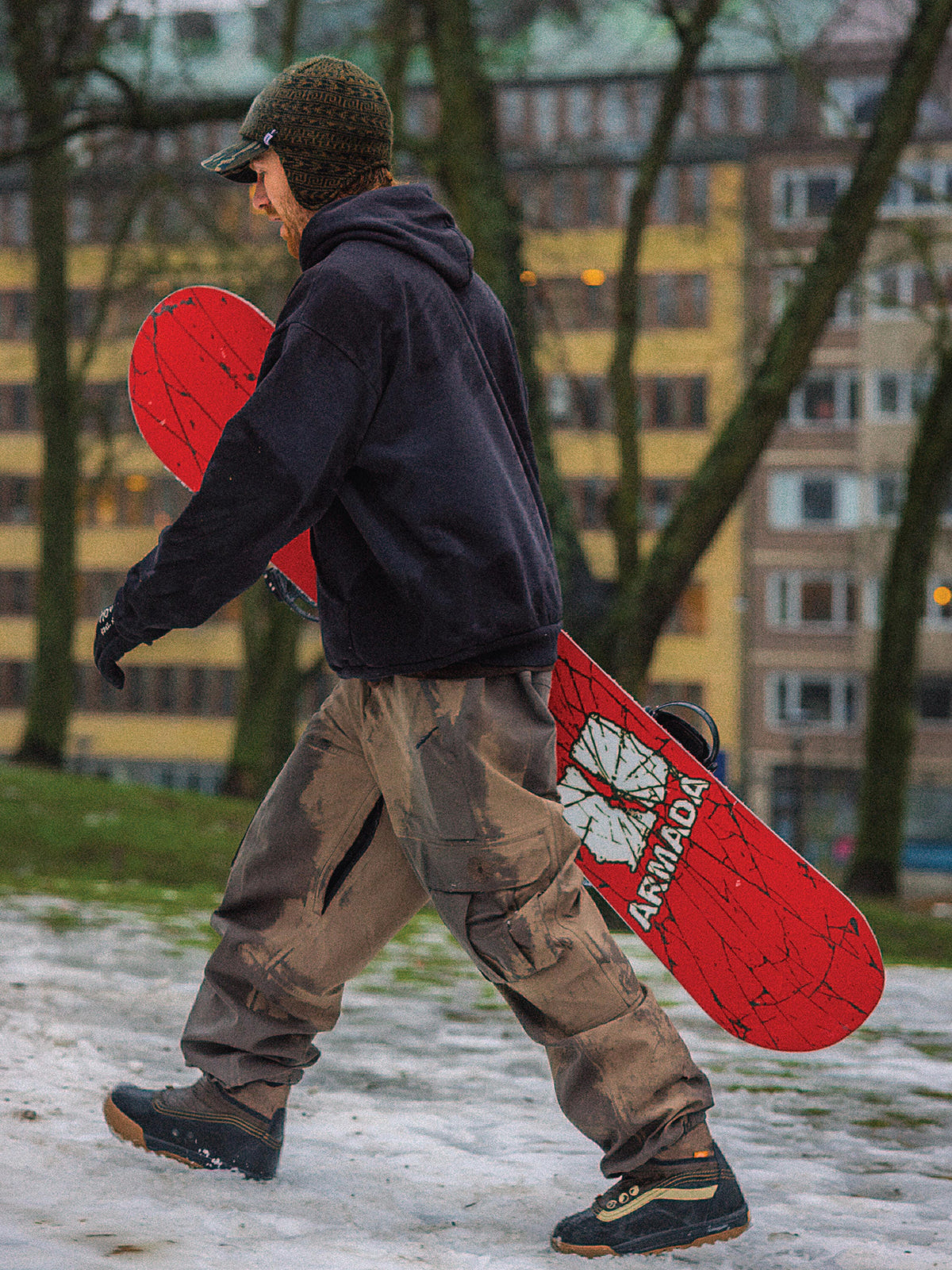 Damnimals walking holding a the 26/27 Beatnik new Armada snowboard witha red base