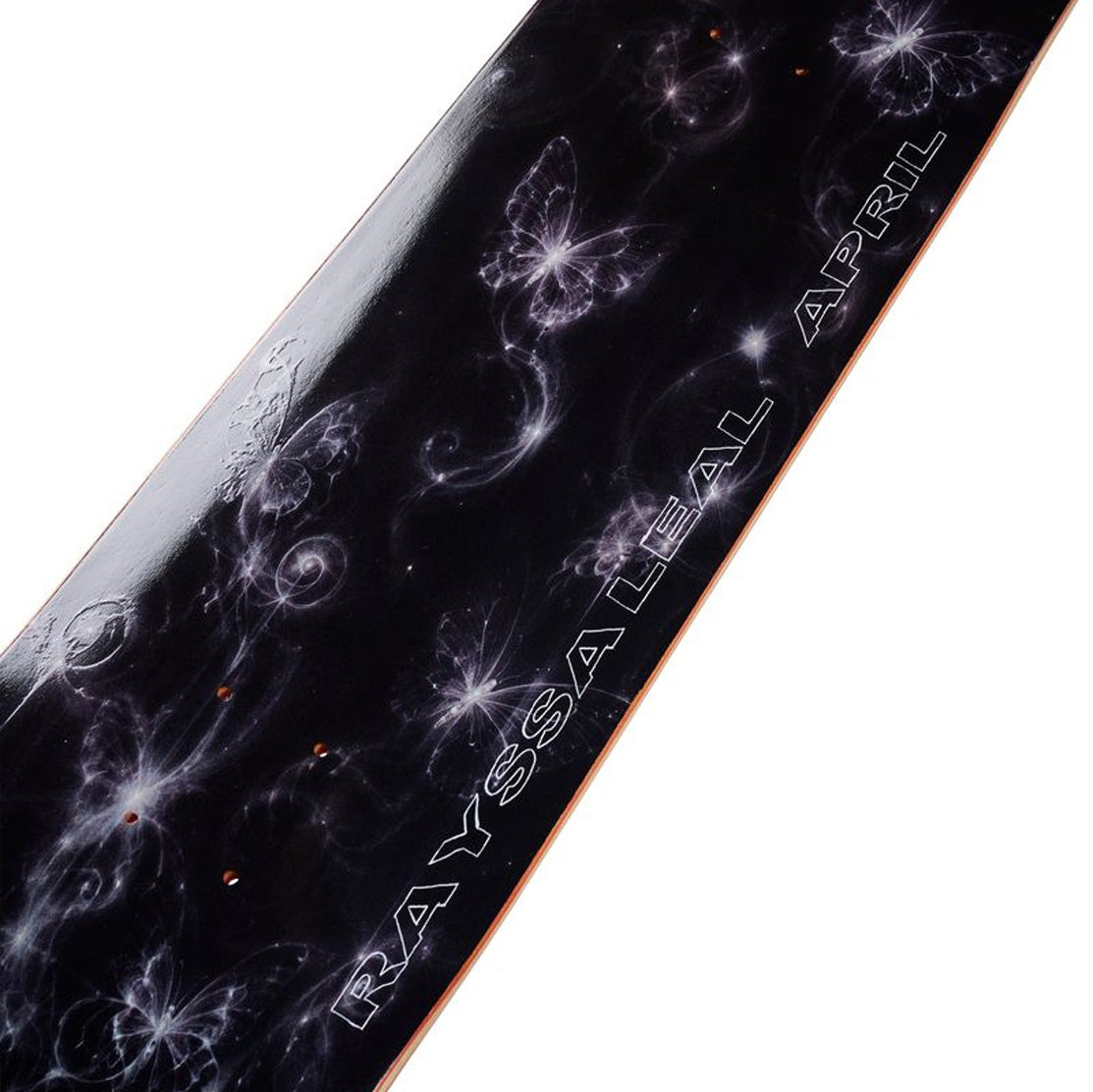 A close-up of April Rayssa Night skateboard deck featuring a glossy black background decorated with white and purple cosmic swirls, stars, and butterfly.