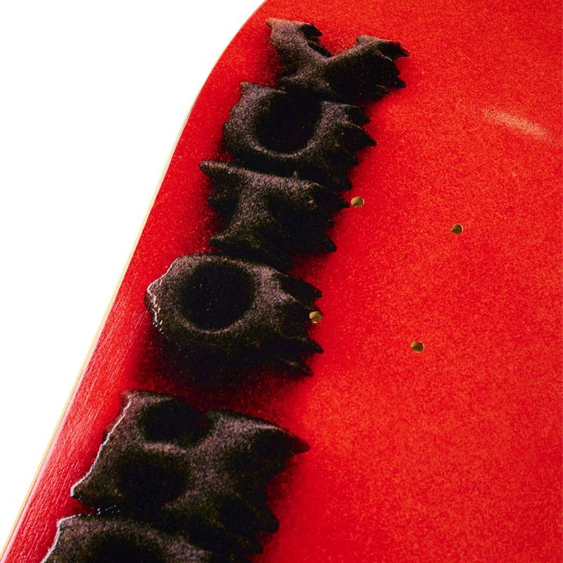 Close-up of a red Yuto April Stamped skateboard deck with black embossed design with red background